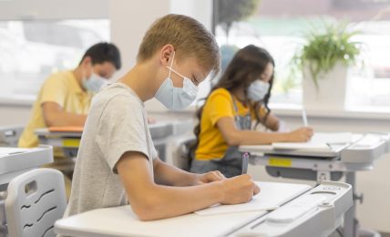 Niños estudiando en clase con mascarilla